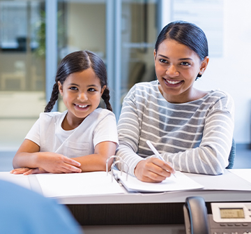 Mother and daughter checking in at dental office reception desk