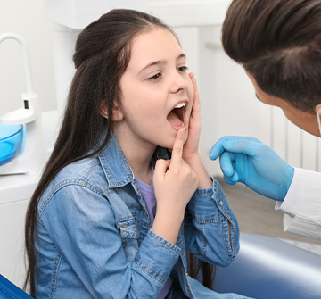 Child pointing to smile during emergency dentistry