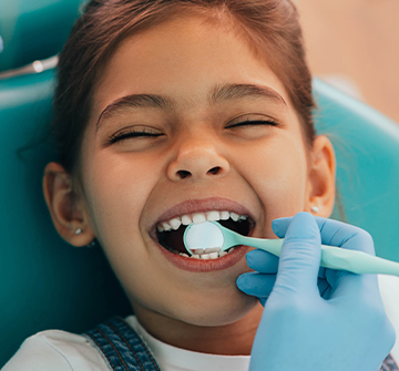 Dentist checking child's dental sealants