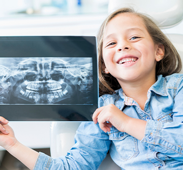 little girl holding up tablet with her digital dental x-rays
