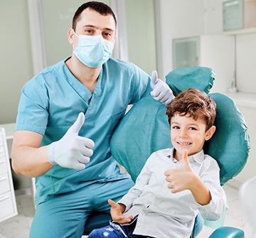 Child and dentist giving thumbs up in treatment room