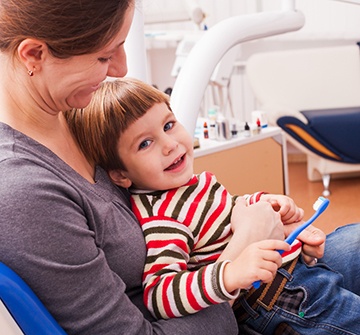 Smiling child sitting in parent's lap at dentist's office