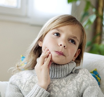 Closeup of young girl experiencing toothache