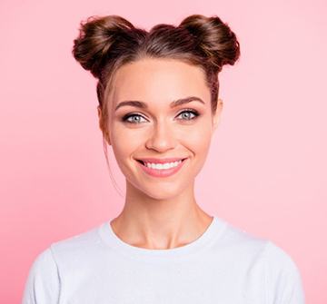 woman smiling against pink background with teeth straightened by Invisalign in Randolph 