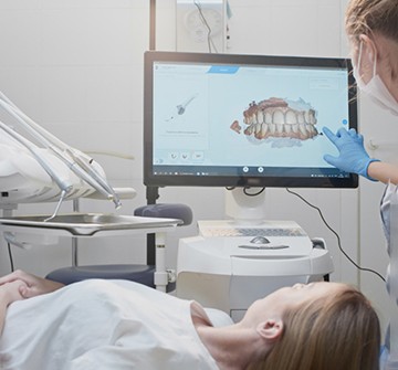 Dental assistant looking at scans of patient's teeth
