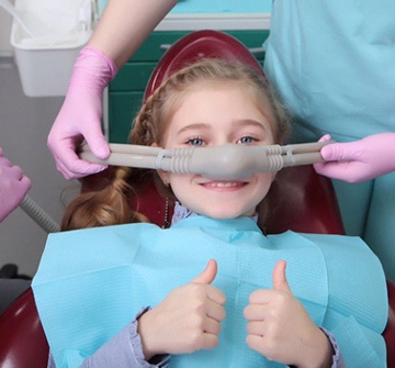 Child giving thumbs up with nasal mask on