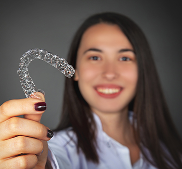 Teen girl holding up Invisalign tray