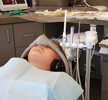 Child in dental office with nitrous oxide mask in place and noise canceling headphones
