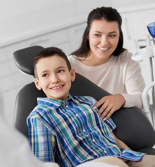 Mother with young boy smiling in dental chair