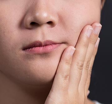 Closeup of teen in need of tooth extraction holding jaw