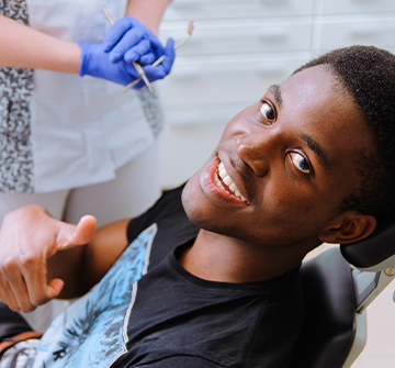 Teen boy giving thumbs up after receiving dental sealants
