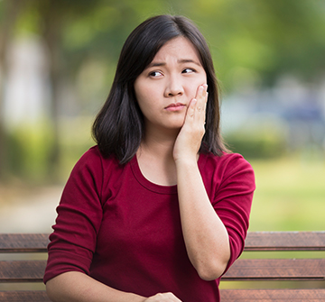 Teen in need of emergency dentistry holding cheek