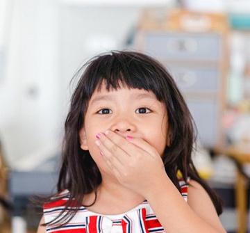 Young girl covers her mouth before getting a tooth-colored filling for kids in Randolph