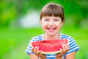 Girl with watermelon and braces in summer outside