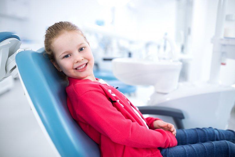 Child smiling while sitting in dentist's treatment chair