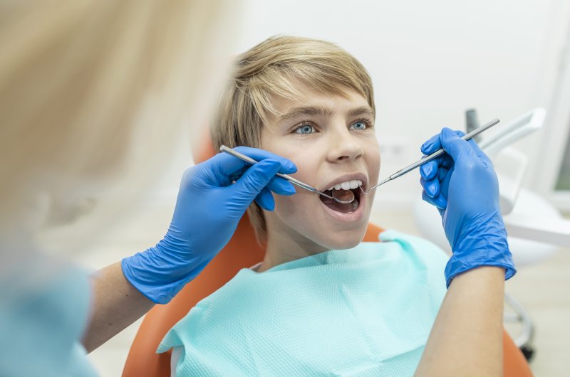 Pediatric dentist checking teen's teeth and gums
