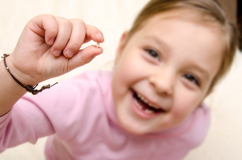 Closeup of little girl holding her baby tooth