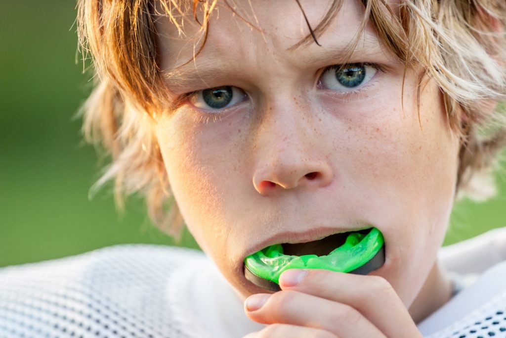 Young athlete putting on mouthguard