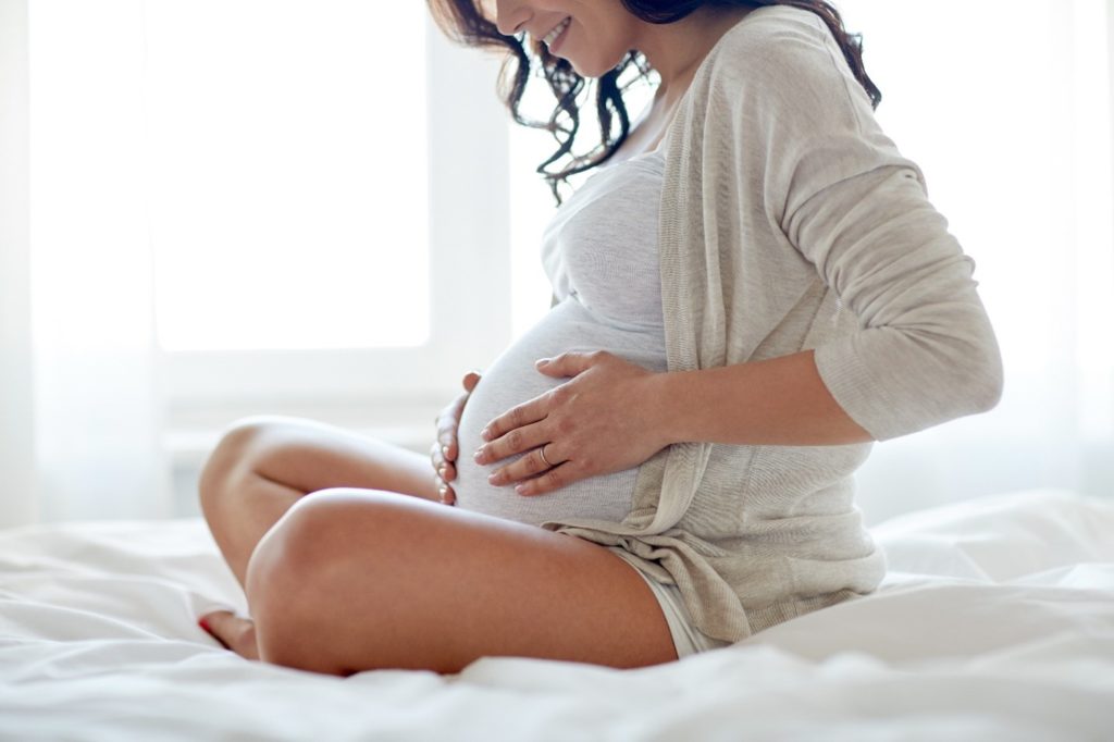 Pregnant woman smiling while touching belly