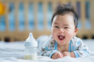 Laughing baby next to baby bottle