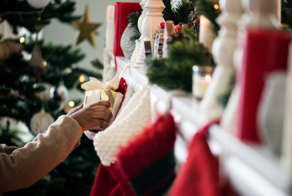 Child pulling gift out of stocking on fireplace