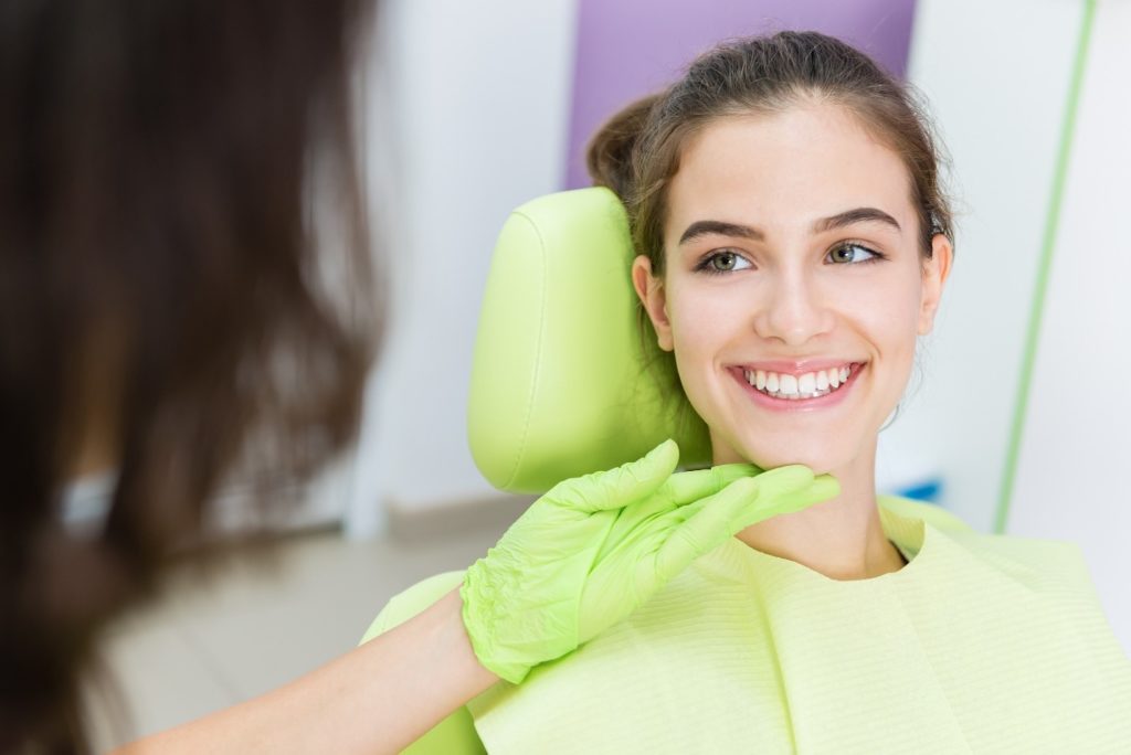 Pediatric dentist looking at teenager's smile