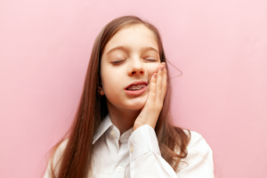a young teen with braces holding her cheek